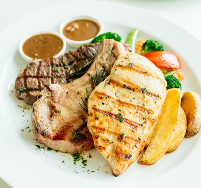 Grilled Chicken breast and Pork chop with beef meat steak and vegetable in white plate