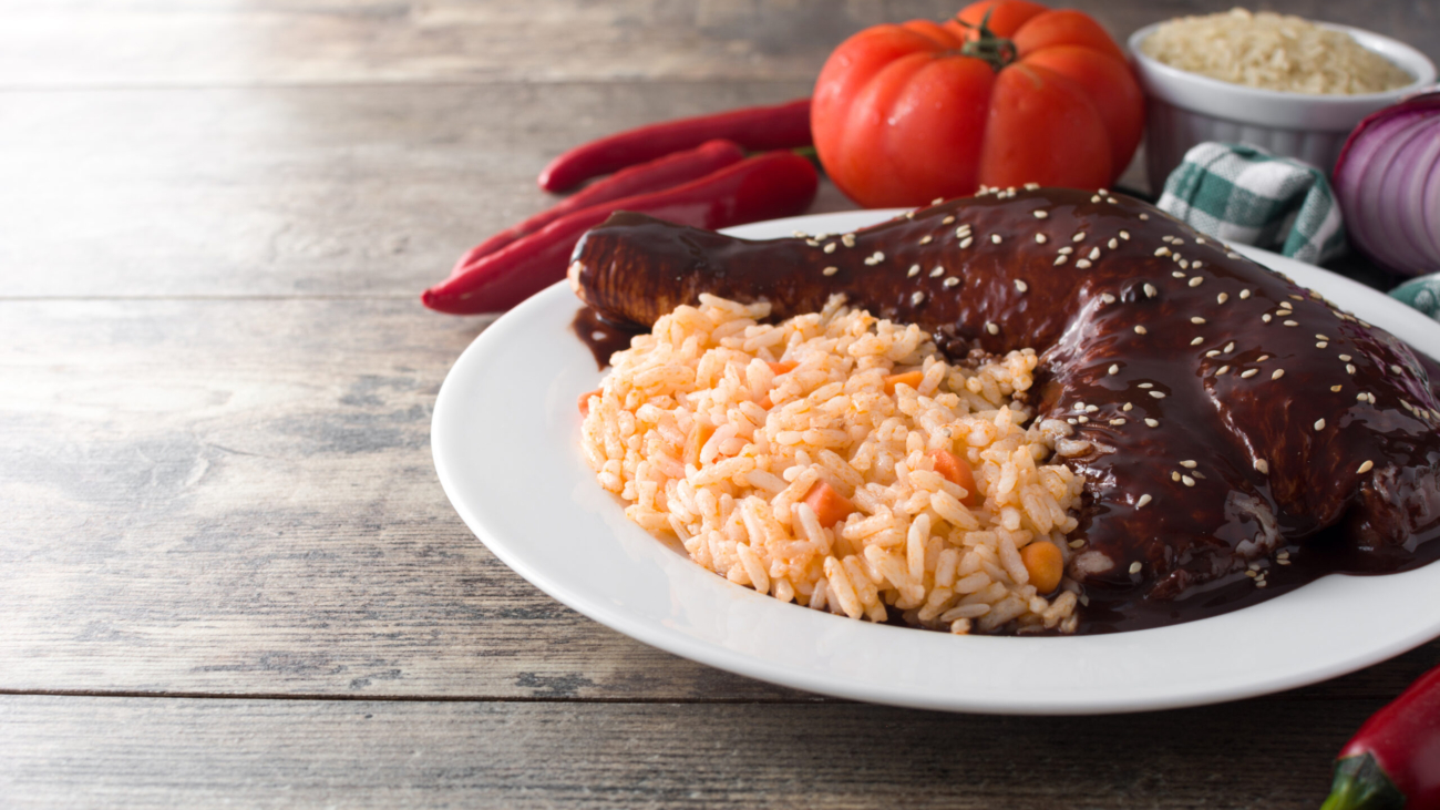 Traditional mole Poblano with rice in plate on wooden table